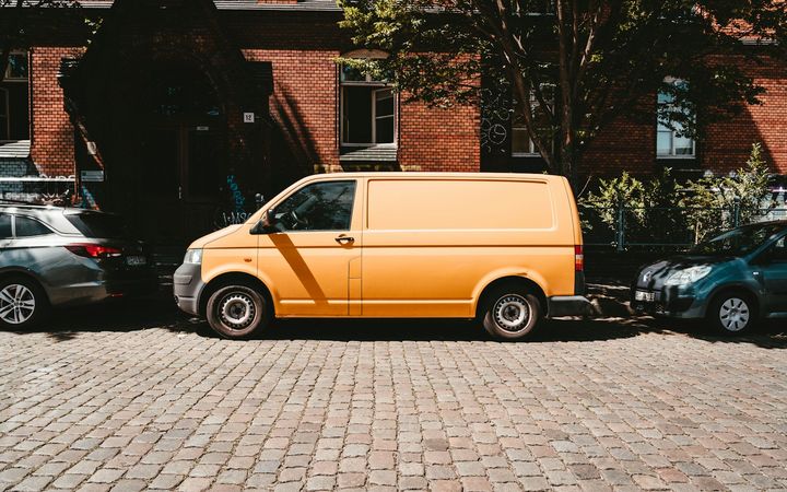 Weißer Transporter parkt vor einem Backsteinhaus in der Stadt