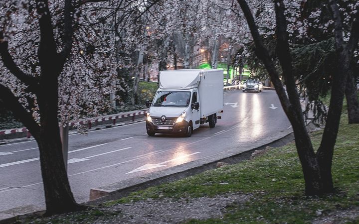 Umzugshelfer schiebt gestapelte Kartons mit der Sackrodel zu einem weißen Transporter