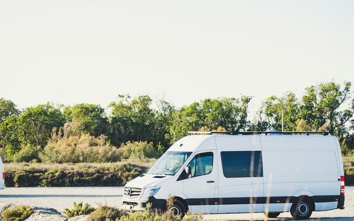 Weißer Transporter auf einer Landstraße zwischen grünen Hügeln