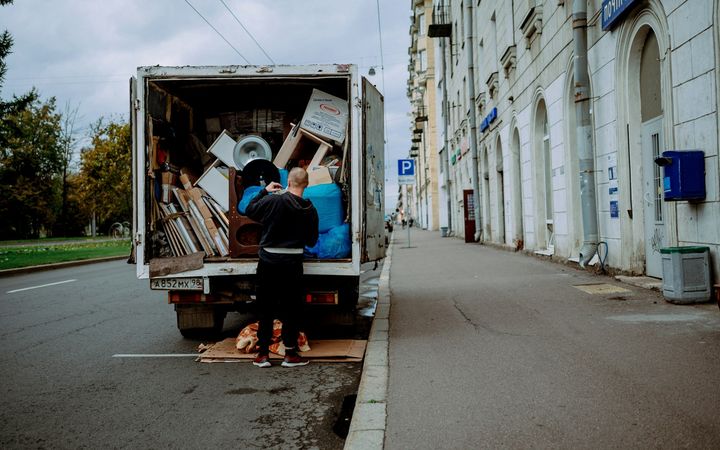 Umzugshelfer lädt Möbel aus einem Umzugswagen in einer Wiener Straße